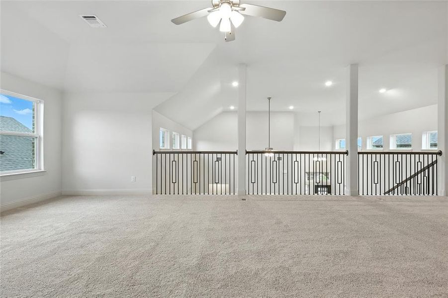 Carpeted spare room featuring ceiling fan, healthy amount of natural light, lofted ceiling, and recessed lighting