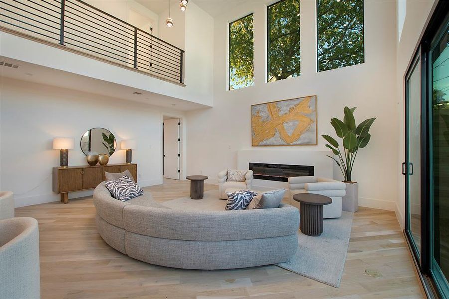 Living room with light hardwood / wood-style floors and a high ceiling