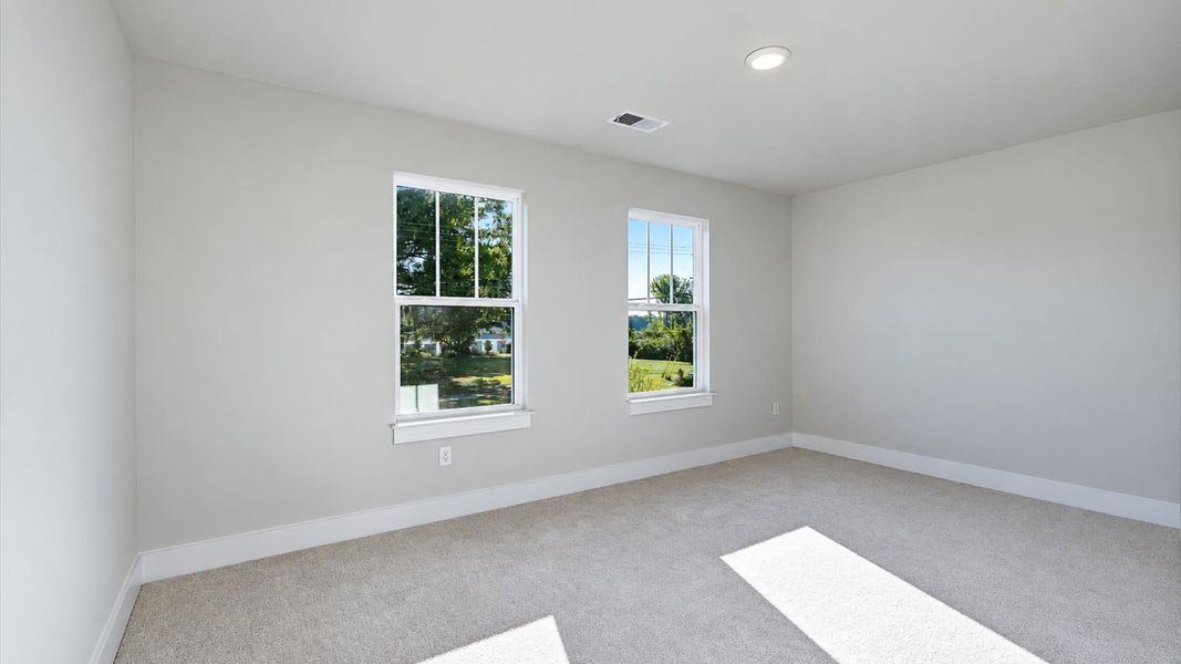 Tasteful bedroom with plush carpet, a walk-in closet, and large windows for abundant natural light by DRB Homes Tasteful bedroom with plush carpet, a walk-in closet, and large windows for abundant natural light by DRB Homes