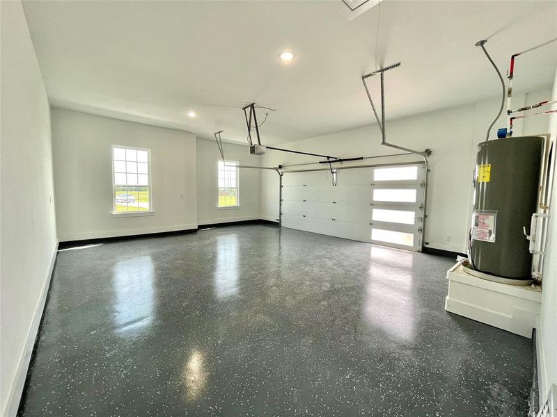 Garage with baseboards, water heater, a garage door opener, and recessed lighting Garage with baseboards, water heater, a garage door opener, and recessed lighting