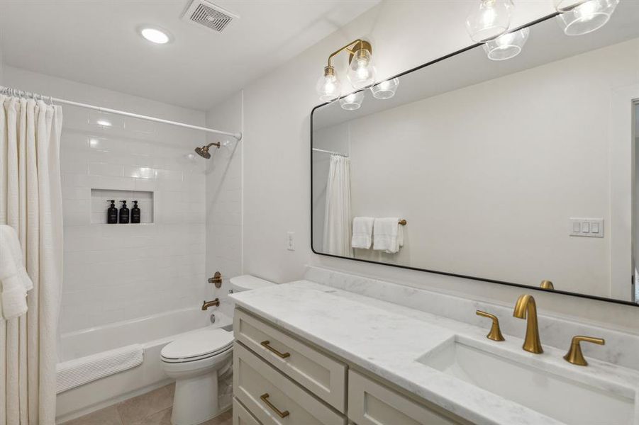 Full bathroom featuring tile flooring, shower / bath combination with curtain, vanity, and toilet