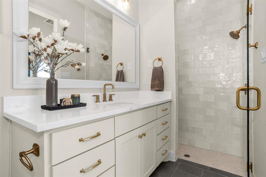 Bathroom featuring a stall shower, vanity, and dark tile patterned floors