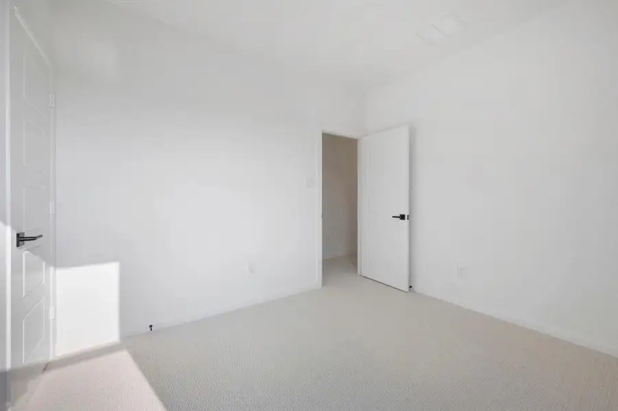 Bright room featuring light-toned carpeting and neutral wall paint