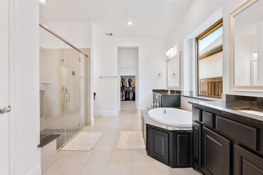 Primary bath boasts separate vanity sinks a nice sized garden tub, a make up vanity, large standing shower with bench, and wonderful natural light.