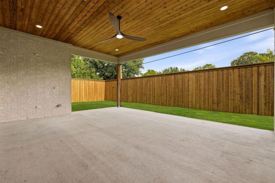 Covered outdoor patio with a wood-plank ceiling, integrated lighting, and a ceiling fan