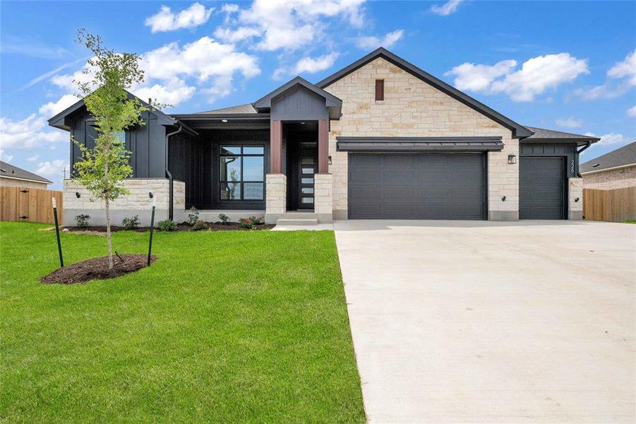 View of front of property with a garage, a front lawn, board and batten siding, and fence