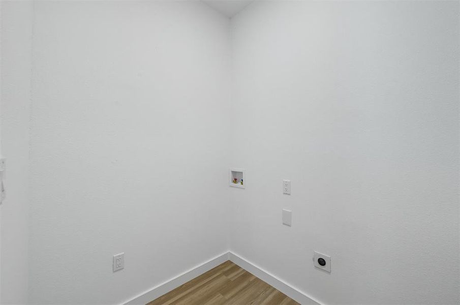 Laundry area featuring light wood-style floors, hookup for a washing machine, and electric dryer hookup Laundry area featuring light wood-style floors, hookup for a washing machine, and electric dryer hookup