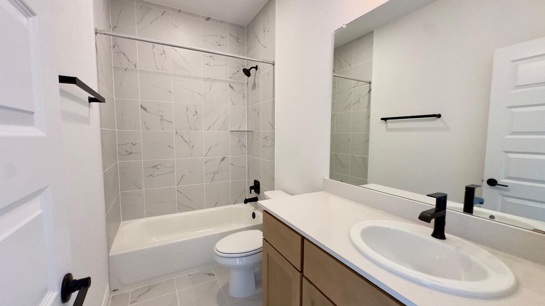 Bathroom featuring vanity, shower / washtub combination, and light marble finish flooring