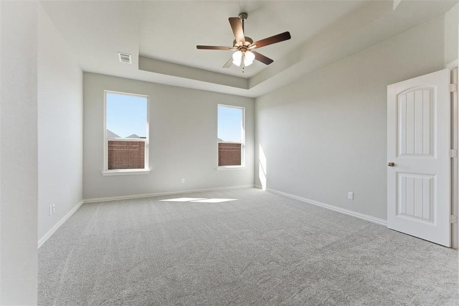 Spare room with light colored carpet, a tray ceiling, and ceiling fan