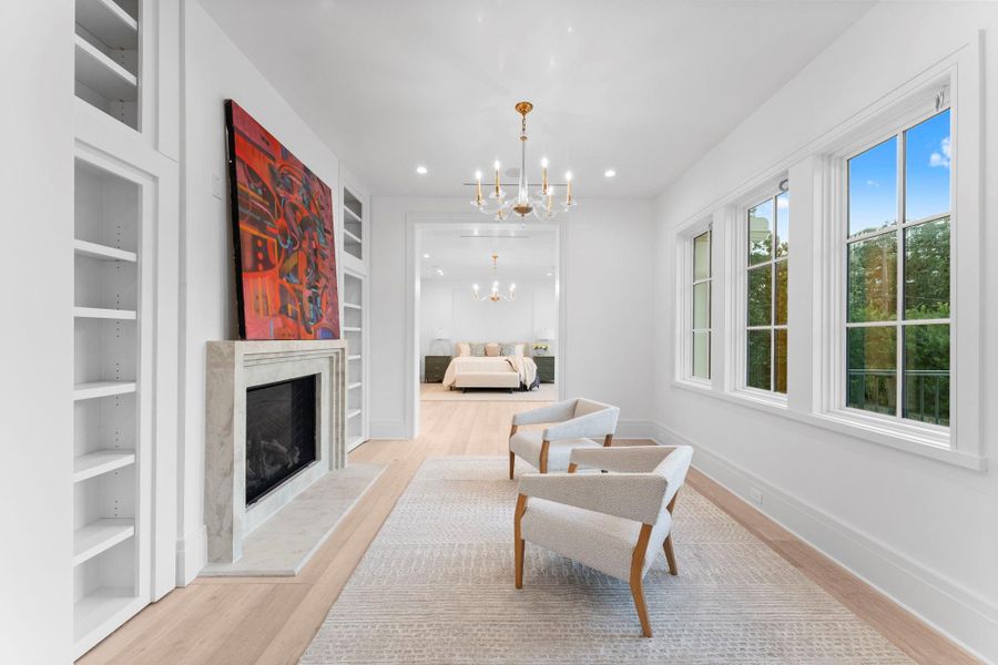 The primary sitting room features a stunning chandelier, custom built-in shelving and gas log fireplace The primary sitting room features a stunning chandelier, custom built-in shelving and gas log fireplace