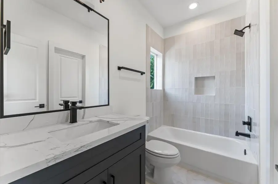 Ensuite bathroom with shaker cabinets and quartz countertops.