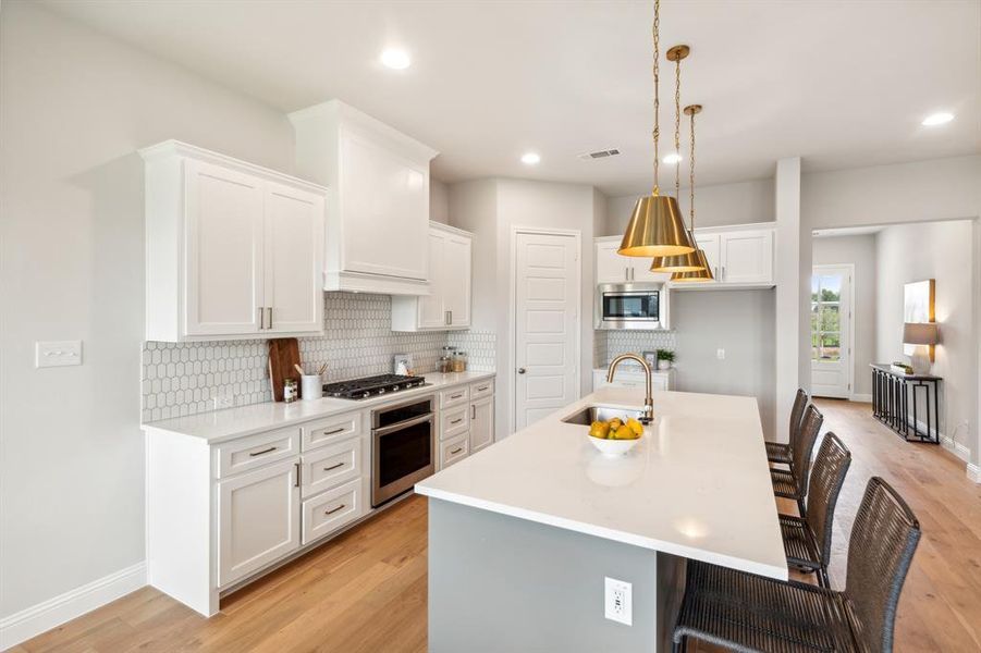 Kitchen with sink, white cabinetry, a center island with sink, and stainless steel appliances