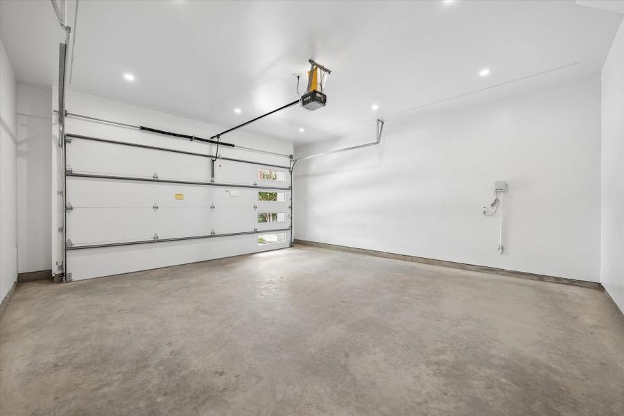 Spacious and well-lit 2 car garage with clean concrete flooring, modern automatic door, and ample room for storage or parking. Spacious and well-lit 2 car garage with clean concrete flooring, modern automatic door, and ample room for storage or parking.
