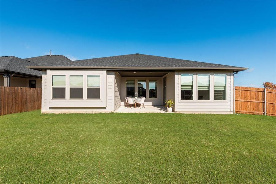 Back of house featuring a fenced backyard, a patio, and a shingled roof