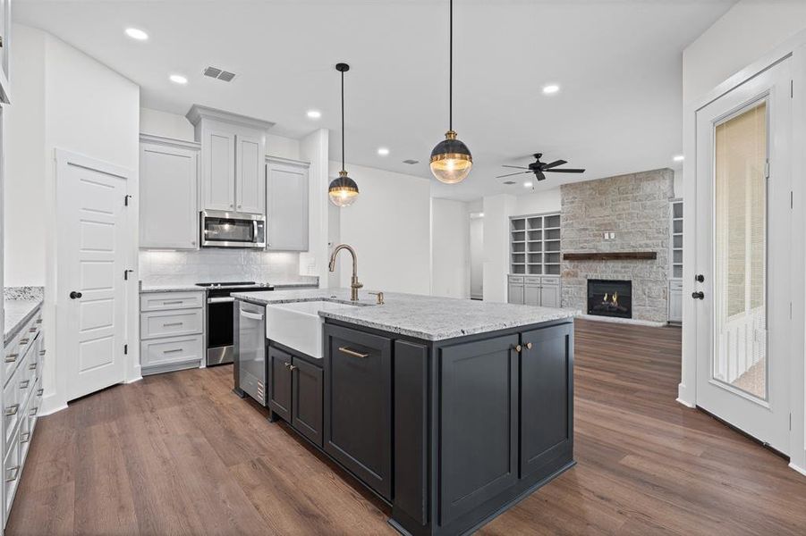 The kitchen features an island with a farmhouse sink and granite countertops, complemented by stainless steel appliances