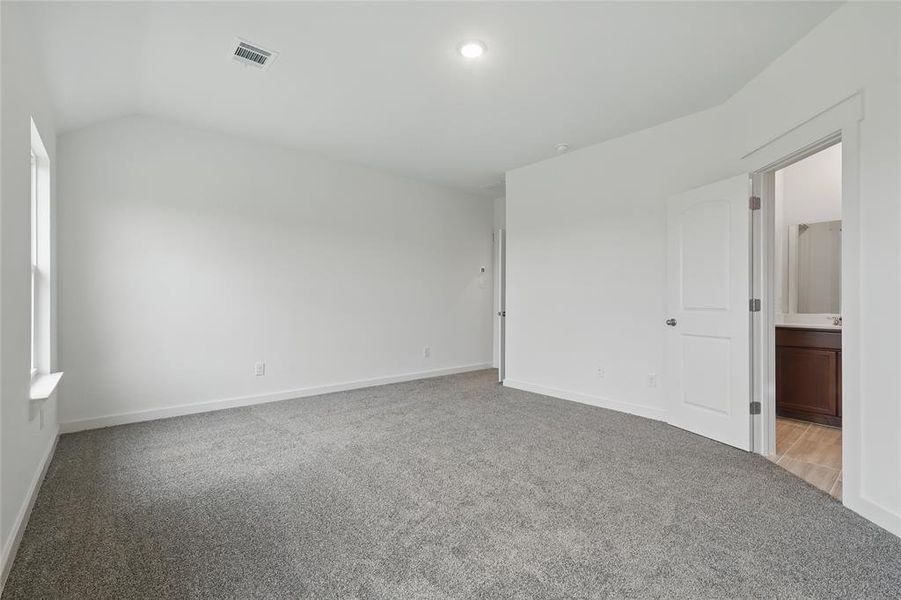 Unfurnished bedroom featuring light carpet, ensuite bath, and vaulted ceiling Unfurnished bedroom featuring light carpet, ensuite bath, and vaulted ceiling