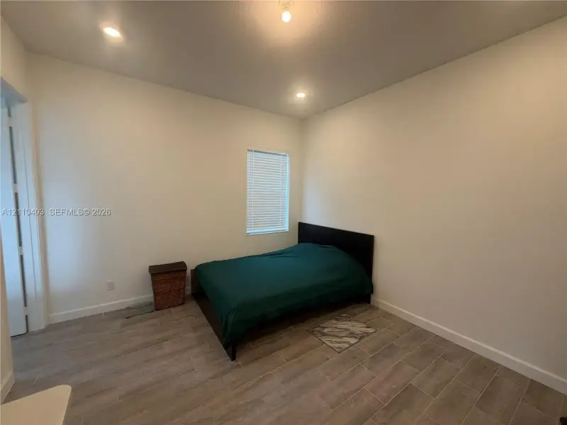 Room featuring neutral wall paint, wood-finish tile flooring, recessed lighting, and a window with blinds