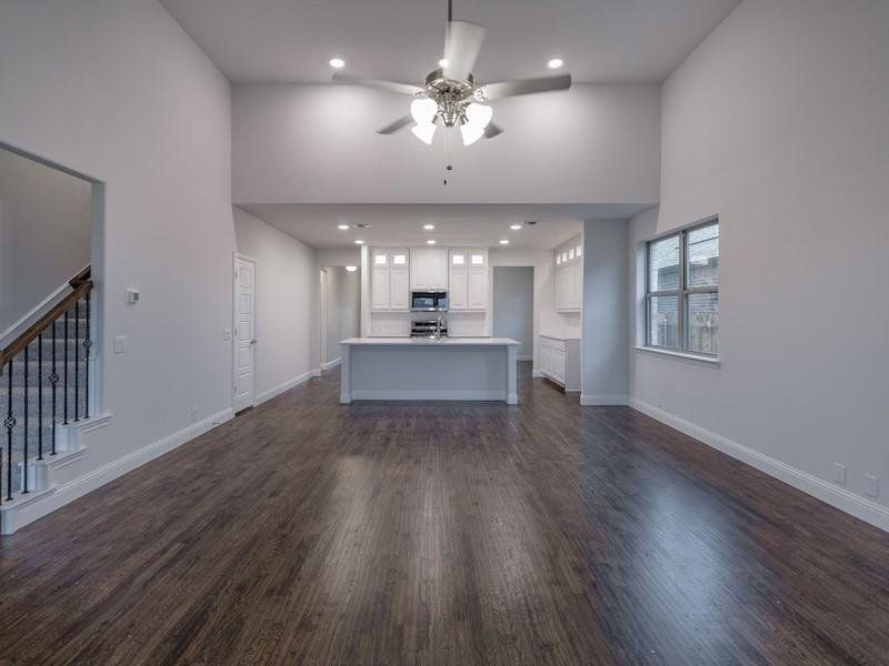 Unfurnished living room with dark hardwood / wood-style flooring, a towering ceiling, and ceiling fan