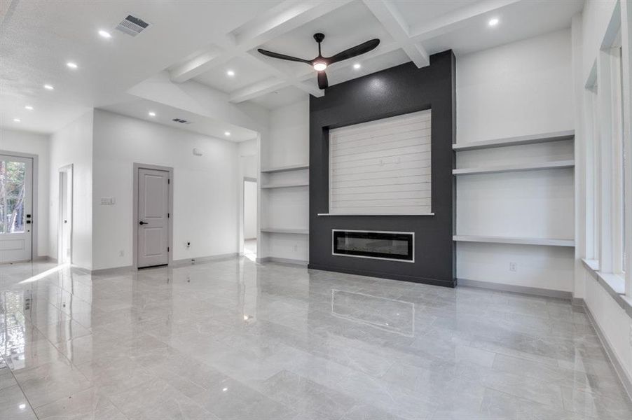 Unfurnished living room featuring a fireplace, beamed ceiling, ceiling fan, and coffered ceiling