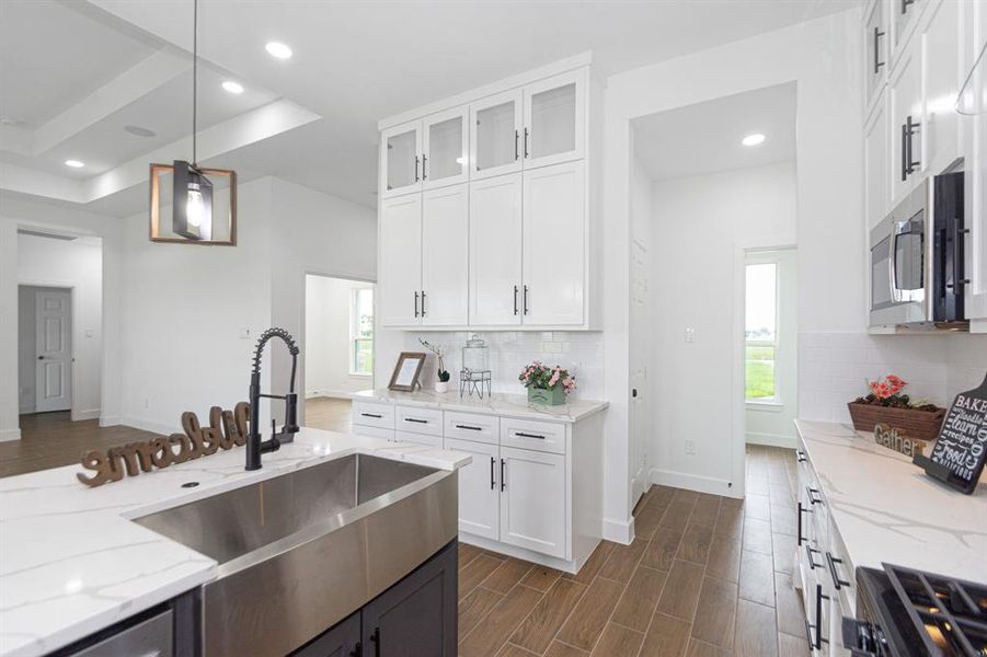 Farm style sink with modern plumbing fixtures.  Coffee bar area with custom soft closing wood cabinets to the ceiling.