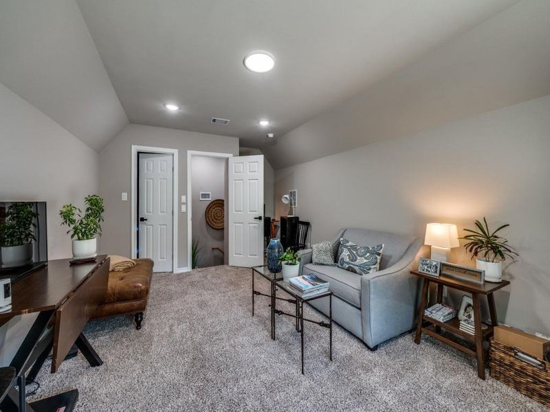 Living area featuring carpet floors, vaulted ceiling, a desk, and baseboards Living area featuring carpet floors, vaulted ceiling, a desk, and baseboards