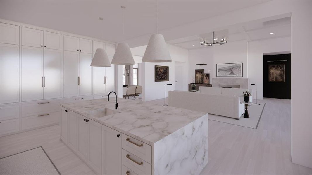 Kitchen with a sink, white cabinets, light stone countertops, an island with sink, and decorative light fixtures