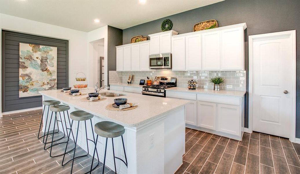 Kitchen with backsplash, appliances with stainless steel finishes, a breakfast bar area, a center island with sink, and white cabinetry Kitchen with backsplash, appliances with stainless steel finishes, a breakfast bar area, a center island with sink, and white cabinetry
