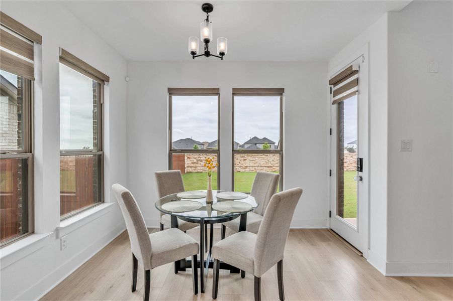 A well-lit breakfast area featuring light wood flooring and a door opening to a private yard.