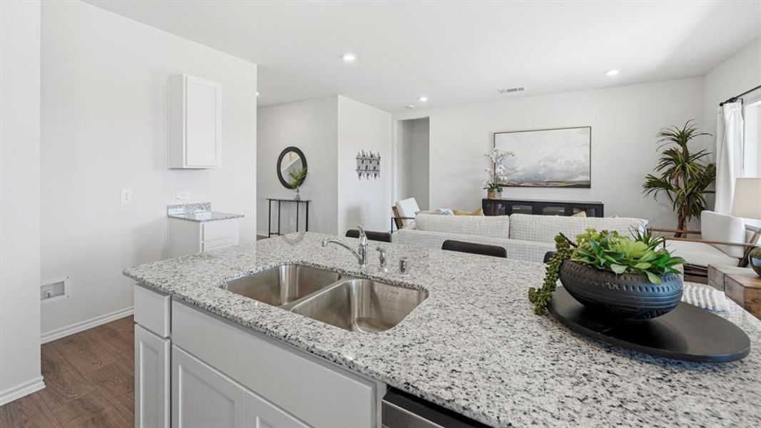 Kitchen featuring white cabinetry, open floor plan, light stone countertops, dark wood finished floors, and recessed lighting Kitchen featuring white cabinetry, open floor plan, light stone countertops, dark wood finished floors, and recessed lighting
