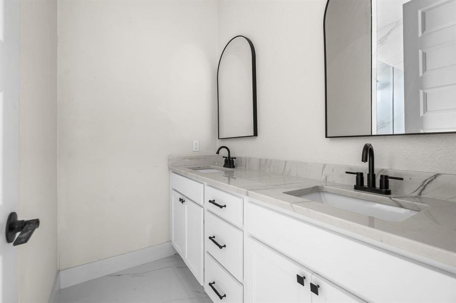Bathroom featuring double vanity and light marble finish flooring
