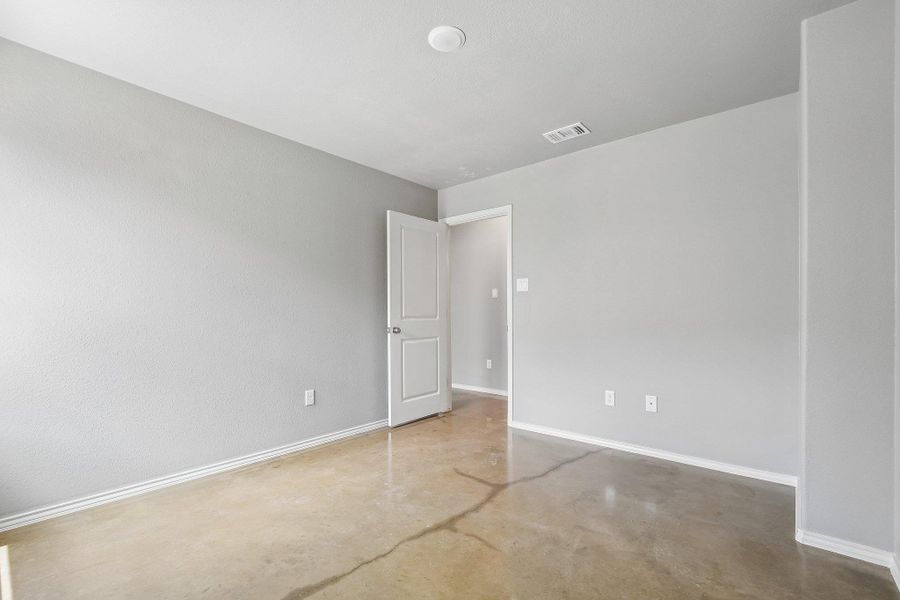 An airy bedroom with polished concrete floors offers a clean, modern aesthetic. An airy bedroom with polished concrete floors offers a clean, modern aesthetic.