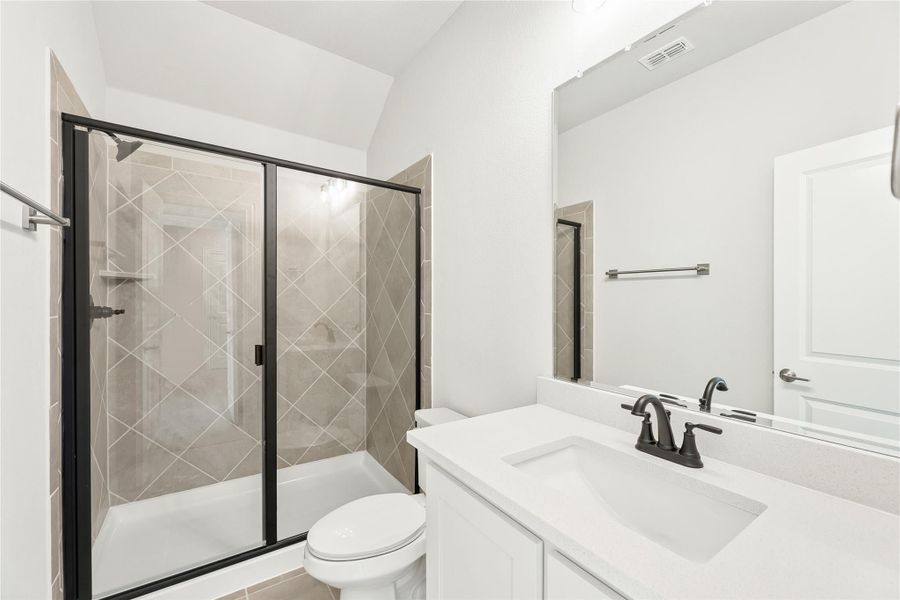 Bathroom with glass-door shower, tiled walls, white vanity, and black fixtures Bathroom with glass-door shower, tiled walls, white vanity, and black fixtures