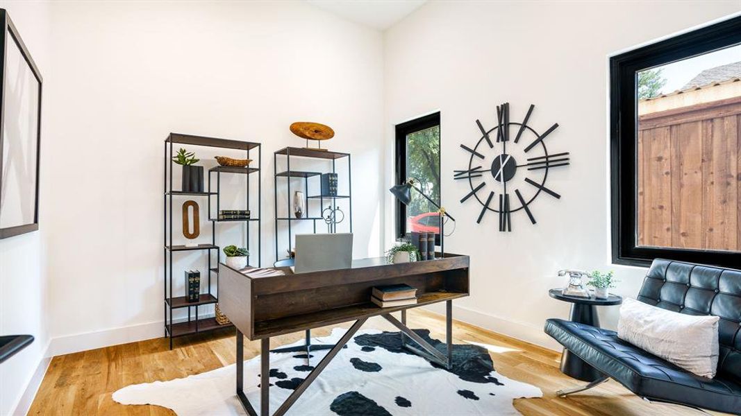 Office space with high vaulted ceiling and light wood-type flooring