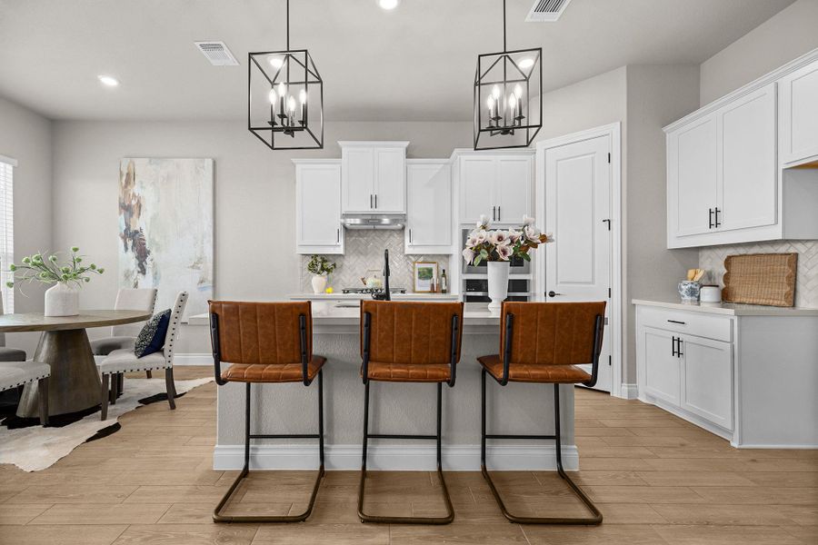 Kitchen featuring white cabinetry, a kitchen island with sink, a breakfast bar area, hanging light fixtures, and recessed lighting