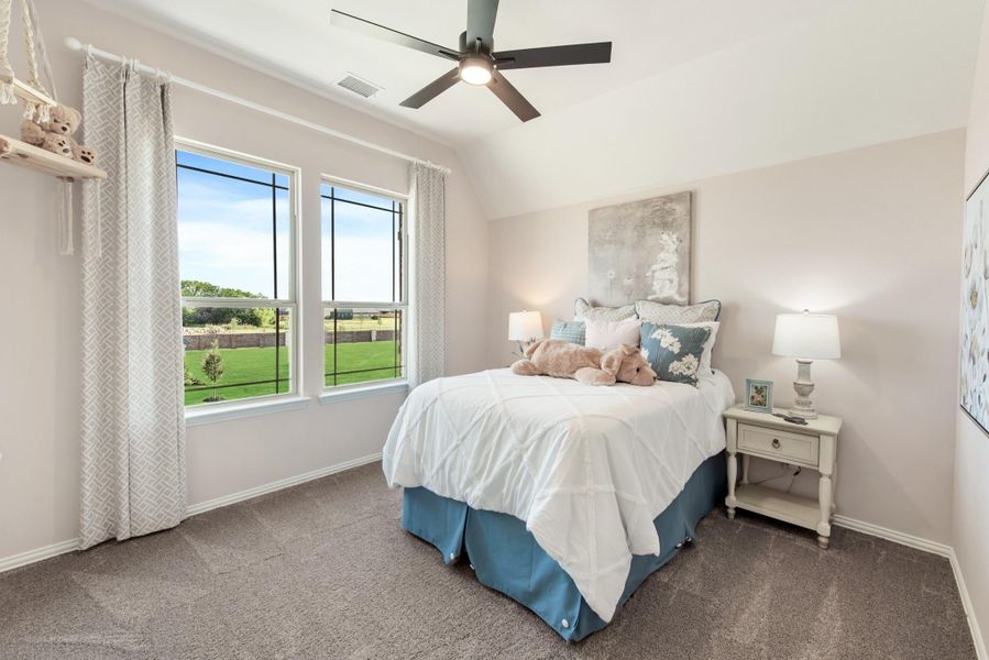 Bedroom with carpeted floor, ceiling fan, large window, and bed with white comforter and blue bed skirt