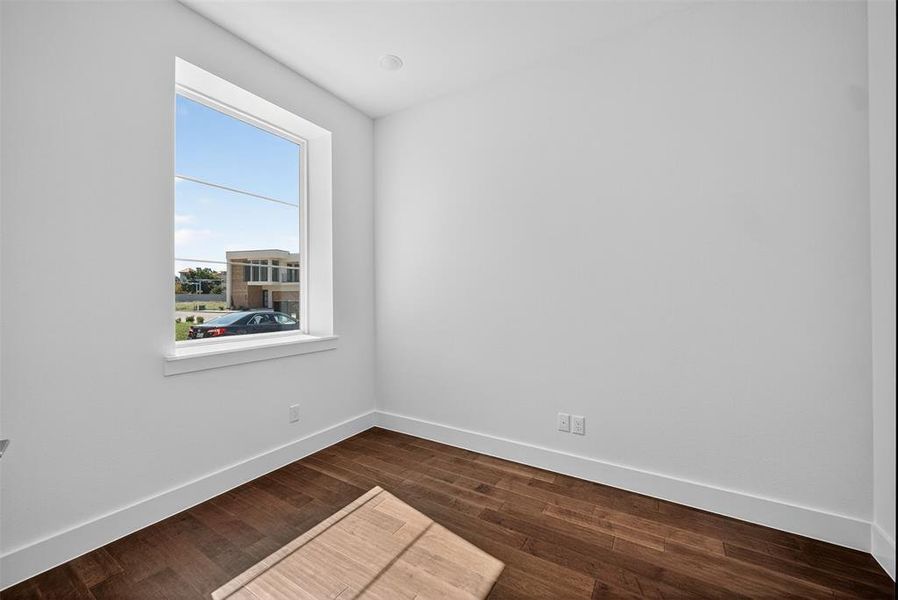 Spare room with baseboards and dark wood-style floors