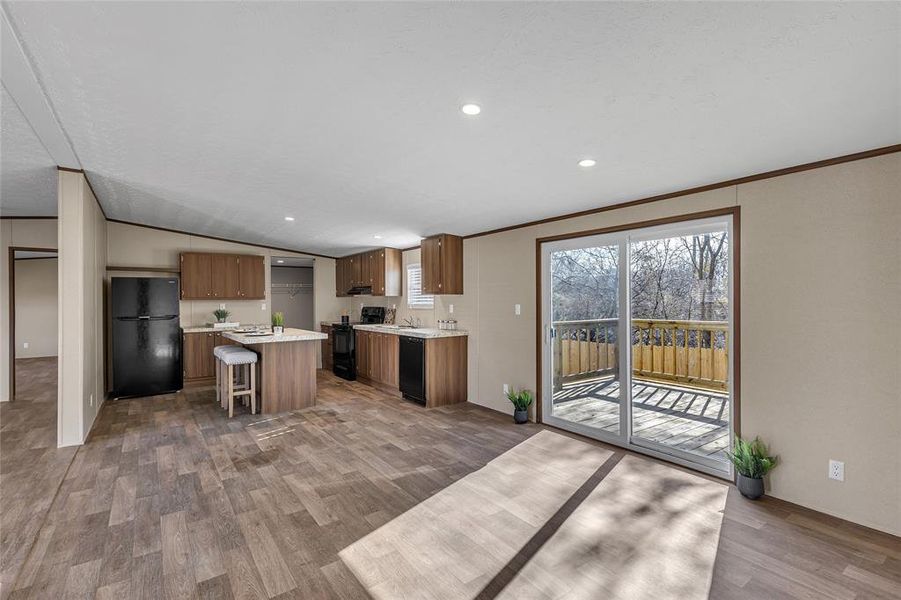 Kitchen featuring a center island, lofted ceiling, a breakfast bar area, wood-type flooring, and black appliances