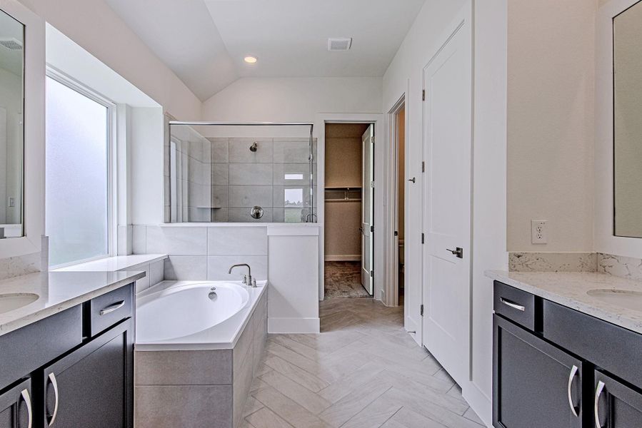 Elegant primary bath complete with dual sinks, soaking tub, and separate shower Elegant primary bath complete with dual sinks, soaking tub, and separate shower