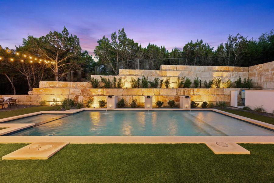 The sparkling in-ground pool and integrated spa feature architectural water elements and custom detailing