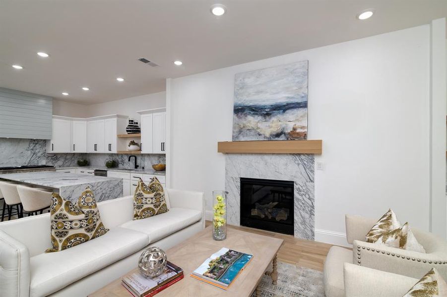 Living room with a premium fireplace, sink, and light hardwood / wood-style flooring