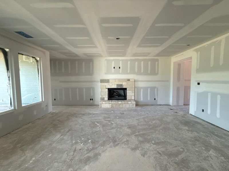 Spacious interior featuring a stone fireplace, coffered ceilings, and multiple large windows Spacious interior featuring a stone fireplace, coffered ceilings, and multiple large windows