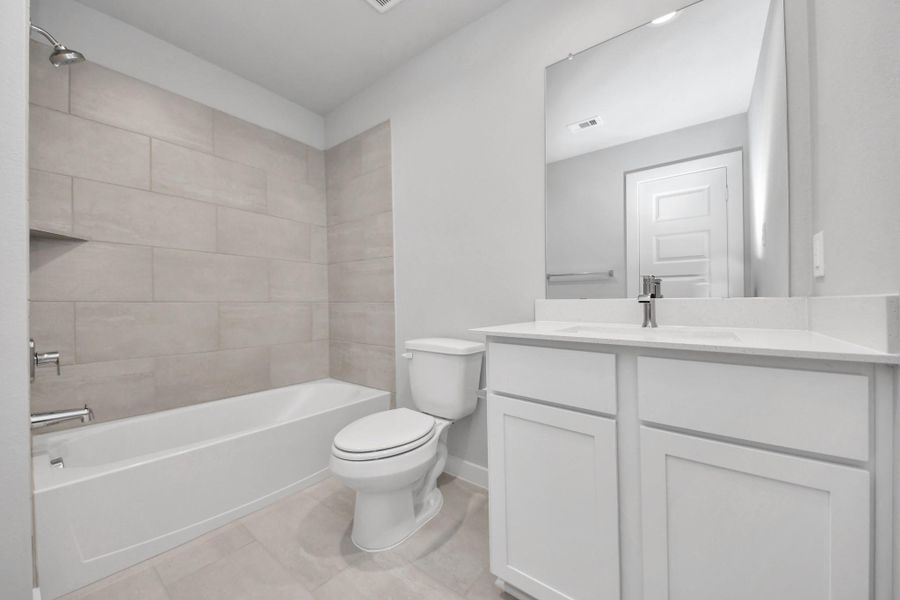 Secondary bath features tile flooring, bath/shower combo with tile surround, light stained wood cabinets, beautiful light countertop. Sample photo of completed home with similar floor plan. Actual colors and selections may vary. Secondary bath features tile flooring, bath/shower combo with tile surround, light stained wood cabinets, beautiful light countertop. Sample photo of completed home with similar floor plan. Actual colors and selections may vary.