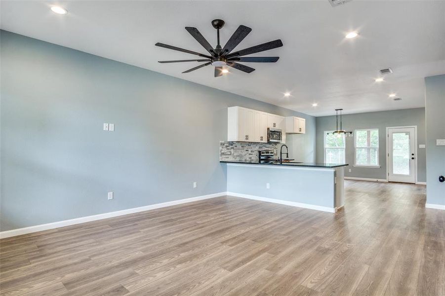 Kitchen with light hardwood / wood-style flooring, kitchen peninsula, white cabinets, ceiling fan, and stainless steel appliances