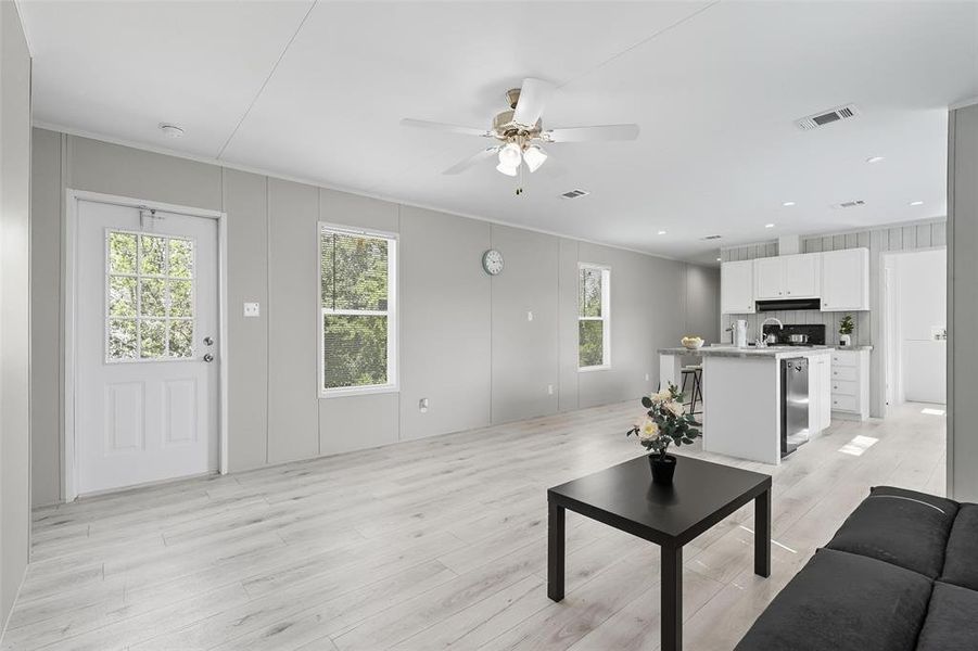 Living room featuring light wood finished floors, ornamental molding, a ceiling fan, and recessed lighting Living room featuring light wood finished floors, ornamental molding, a ceiling fan, and recessed lighting