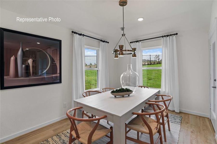 Bright dining area featuring wood-finish flooring, a contemporary chandelier, recessed lighting, and large windows with privacy drapes Bright dining area featuring wood-finish flooring, a contemporary chandelier, recessed lighting, and large windows with privacy drapes