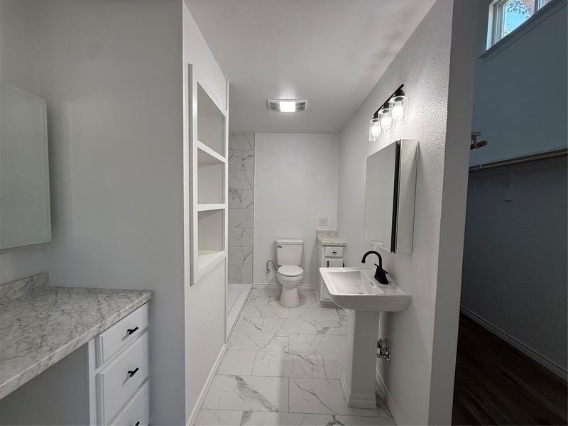Full bath with light marble finish floors, a shower, and a spacious closet