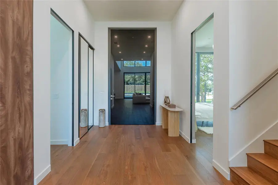 Step into a luminous entryway featuring lustrous hardwood flooring and views into the spacious living areas.
