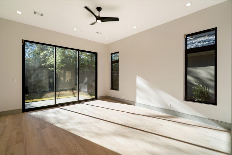 Bright, spacious room with large sliding glass doors and windows, offering plenty of natural light. Features light wood flooring, neutral walls, and a ceiling fan, creating a modern and airy atmosphere. Ideal for relaxation or as a sunroom.