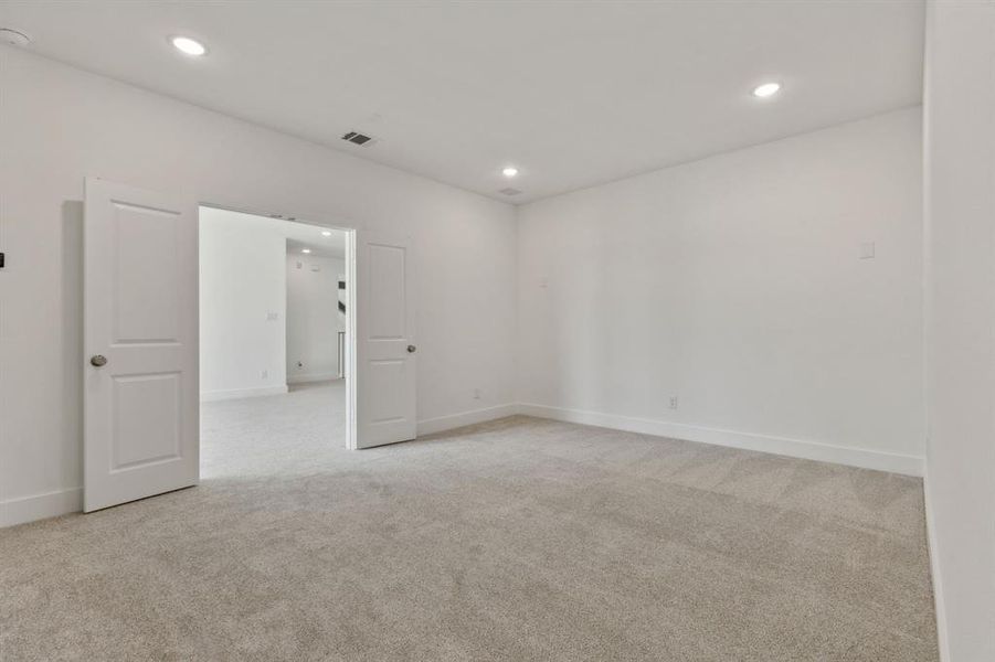 Spacious room featuring neutral carpeting and white walls, complete with recessed lighting and double panel doors Spacious room featuring neutral carpeting and white walls, complete with recessed lighting and double panel doors