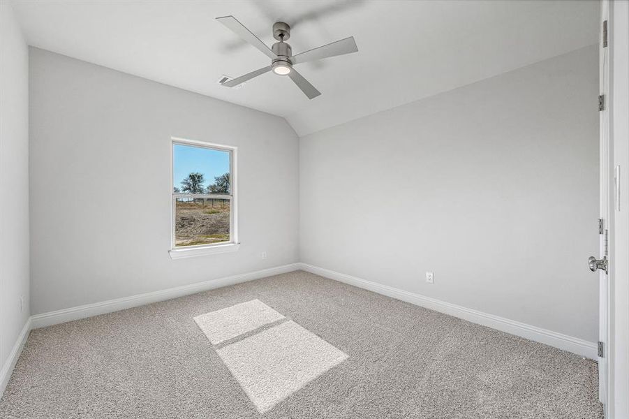 Carpeted spare room with lofted ceiling and a ceiling fan